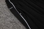 Close-up of black Adidas white tracksuit with zipper and branding details.