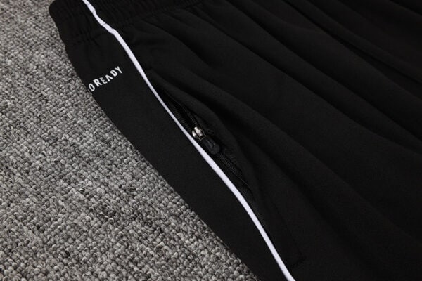 Close-up of black Adidas white tracksuit with zipper and branding details.