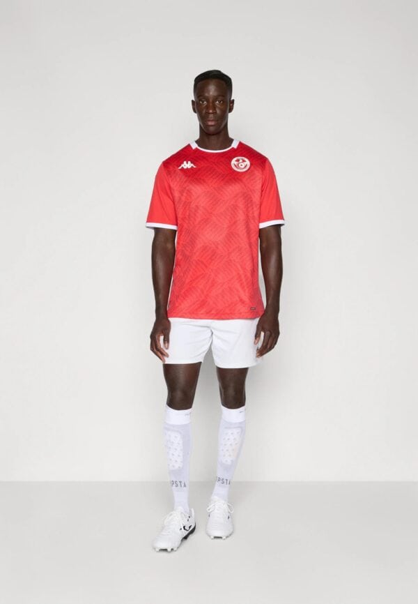 Athletic male soccer player wearing red jersey and white shorts.