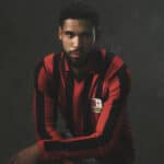Red and black striped football jersey with crest, ideal for soccer fans and players.
