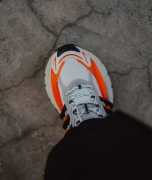 Adidas x Pharrell Williams Adistar sneakers in white, orange, and black. Stylish athletic footwear f.