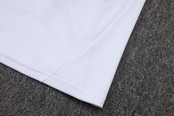 Close-up of white Adidas tracksuit fabric on dark textured background.