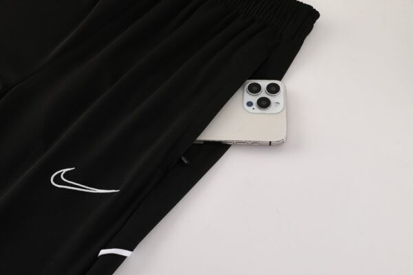 Black Nike Dri-Fit tracksuit with white logo detail, shown with a smartphone tucked into the waistba.