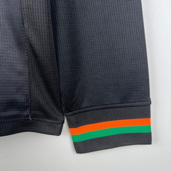 Black football shorts with orange and green stripe accents at the hem.