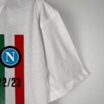 Napoli 2023/24 Scudetto champion football jersey with team logo and colors.