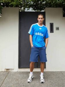 Adidas blue Adicolor T-shirt with white stripes and logo, casual streetwear style.