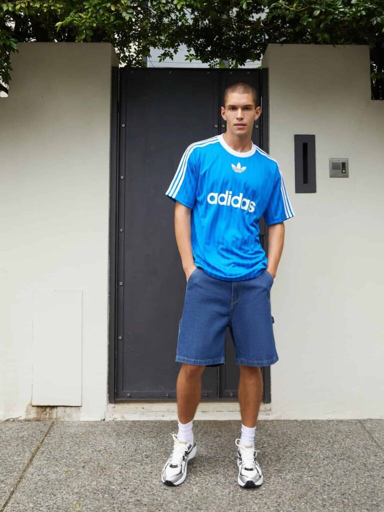 Adidas blue Adicolor T-shirt with white stripes and logo, casual streetwear style.