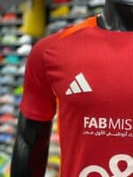 Red Al Ahly training jersey with white logo and sponsor for 2024-2025 season.