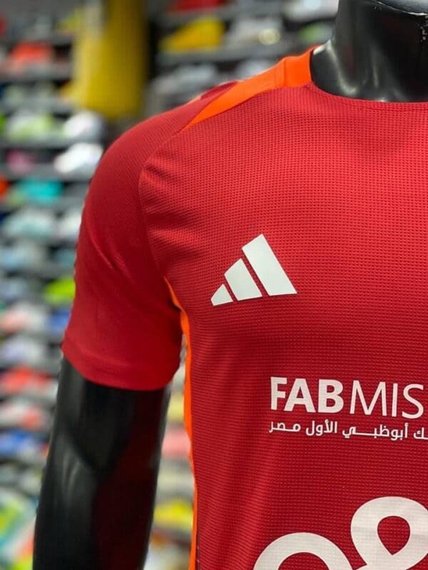 Red Al Ahly training jersey with white logo and sponsor for 2024-2025 season.