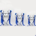 Set of three Champions League trophy replicas in different sizes with blue ribbons.