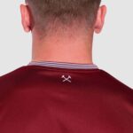 Sports jersey back view with small logo detail on maroon fabric.