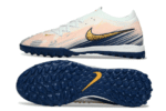 High-performance Nike Phantom GX 2 Elite TF artificial turf soccer shoes in pink, blue, and gold.