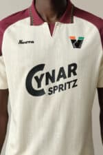 Football jersey with sponsor logos, colorful collar, and team branding for sports fans.