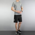 Man wearing Adidas men's sports set with gray shirt and black shorts.
