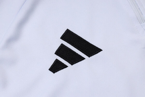 Close-up of Adidas logo on white tracksuit fabric.