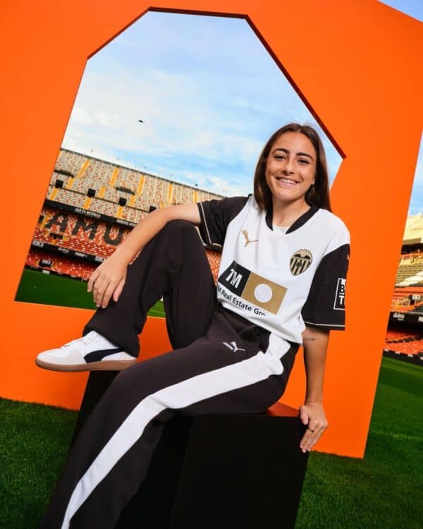 Female football player in Valencia CF kit at stadium.
