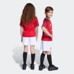 Kids Man United home football kit 2025/26, featuring red jersey and white shorts.