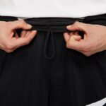 Close-up of men's black athletic sport shorts with drawstring waist.