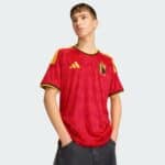 Model wearing a Belgium national team jersey, looking to the left against a pale gray background.