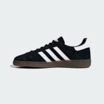 Black Adidas-style sneaker with white stripes on a light gray background (partial view).