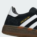 Close-up of a black suede Adidas Spezial sneaker with a white heel trim and gold trefoil logo on the side.