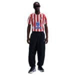 Atlético Madrid 2025/26 home football jersey with red and white stripes, official club logo, and spo.