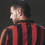 Football jersey with red and black vertical stripes, back view.