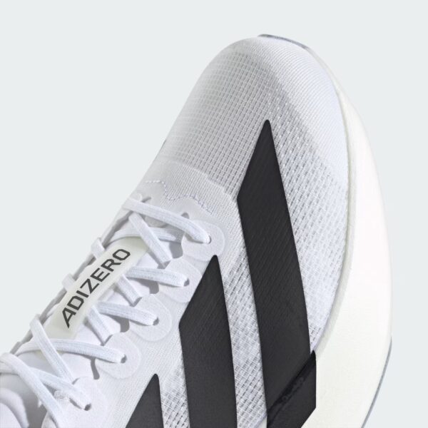 Close-up of a white athletic sneaker with a gray mesh upper, white laces, and a black diagonal stripe on a light background.