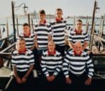 Group of men and boys wearing matching striped football jerseys outdoors.