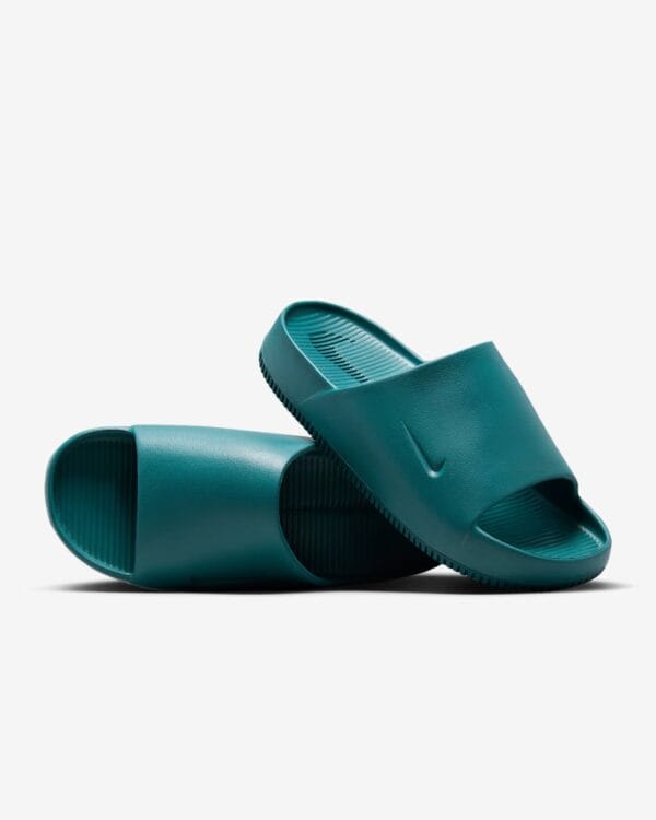 Teal slide sandals stacked on a white background, close-up view of the textured footbed and strap edges.