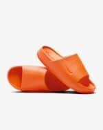 Two bright orange slide sandals with ribbed footbeds placed on a white background, overlapping in a diagonal arrangement.