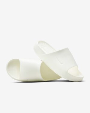 White slide sandals with a textured footbed resting on a light background