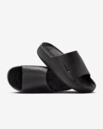 Black slide sandals with a single wide strap and textured footbed on a white background.