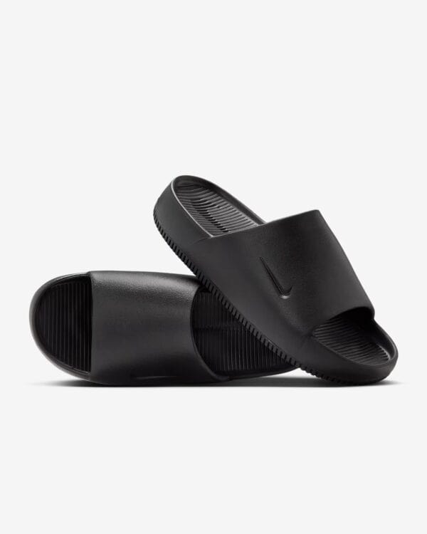 Black slide sandals with a single wide strap and textured footbed on a white background.