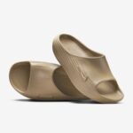 Beige slide sandals with wide ribbed strap shown against a white background, close-up view of the front strap and sole edge.