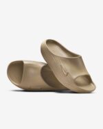 Beige slide sandals with wide ribbed strap shown against a white background, close-up view of the front strap and sole edge.