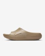 Beige Nike slide sandal on a white background with a ridged sole.