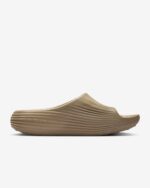 Tan slip-on sandal with a wide, ridged, wavy sole and smooth upper on a white background.
