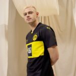 Dortmund away football jersey 2024/25 with black and yellow design, official club logo, and Puma bra.