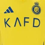 Al Nassr football jersey featuring Ronaldo 7, yellow with blue logo and sponsor text.