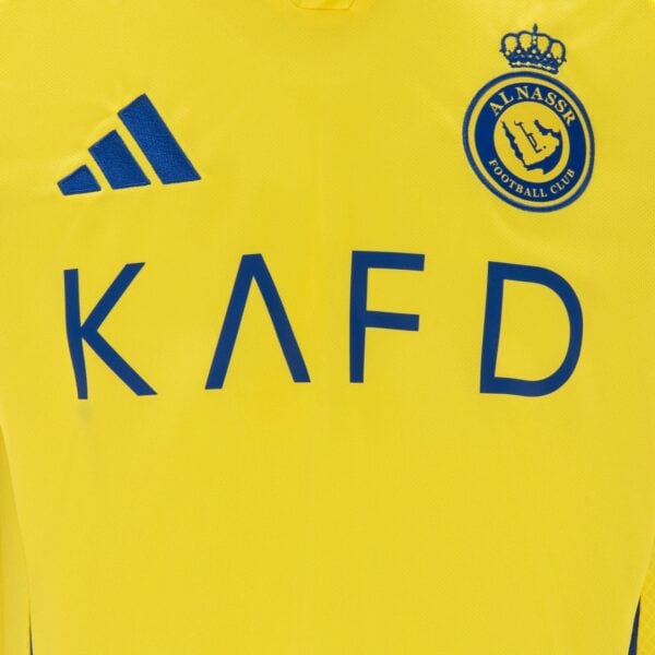 Al Nassr football jersey featuring Ronaldo 7, yellow with blue logo and sponsor text.