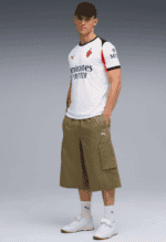 Young male model wearing Arsenal football jersey and cargo shorts.