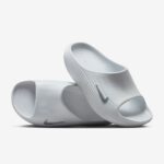 White slide sandals with a ribbed strap and Nike swoosh, shown stacked against a light background.