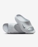 White slide sandals with a ribbed strap and Nike swoosh, shown stacked against a light background.