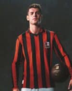 Milan football jersey with red and black vertical stripes, featuring club crest, worn by a young mal.