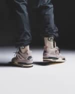 Man wearing Air Jordan 4 Fossil Stone sneakers, close-up view.