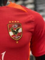 Al Ahly SC training jersey in red with club crest and gold stars, perfect for fans and players.