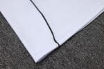 Close-up of white Adidas tracksuit top with black zipper detail.