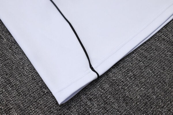 Close-up of white Adidas tracksuit top with black zipper detail.