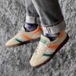 حذاء كرة يد أصلي من adidas بلون بني مع لمسات برتقالية وزرقاء.